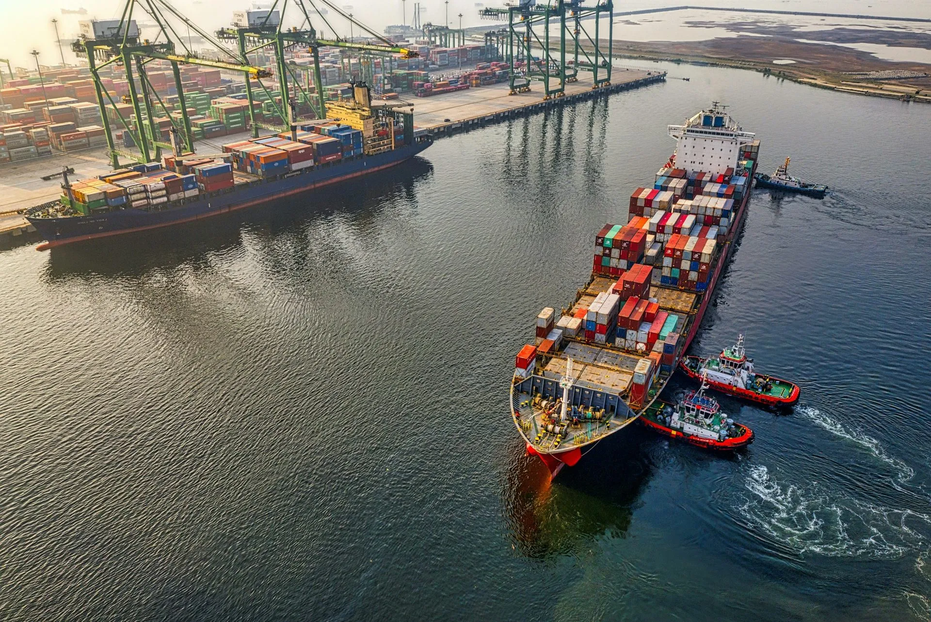 Container ship leaving port with tugboats alongside